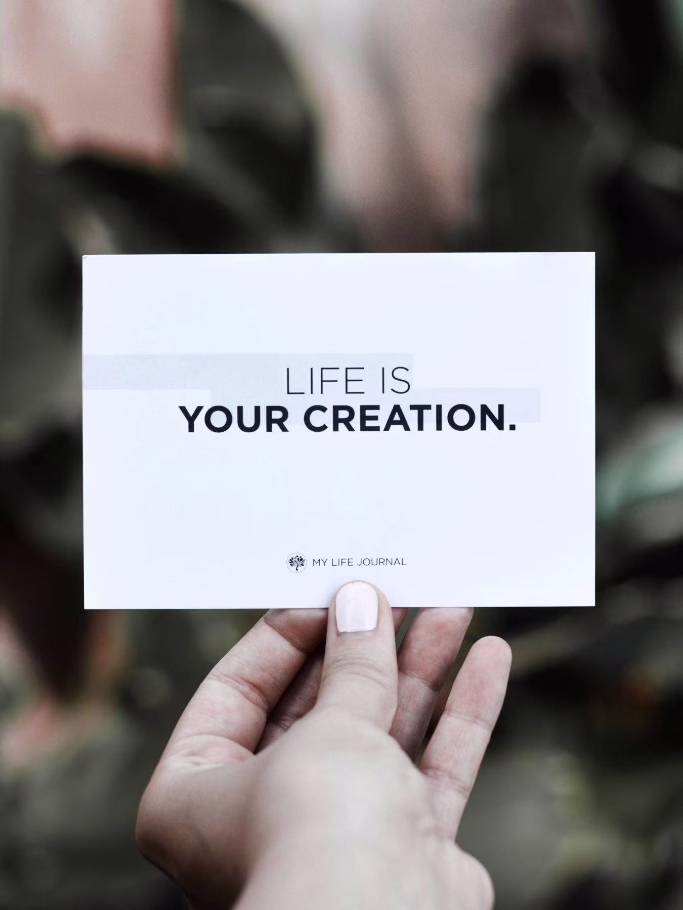 Hand houdt kaartje vast met tekst Life is your creation vet en My Life Journal logo inspirerende zelfontplooiing